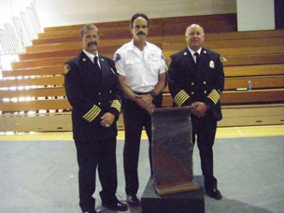 L-R: Asst. Chief of Operation George Brown, Firefighter/Paramedic Mike Garvey, VIFR Fire Chief Hank Lipe standing with Artifact #I-0082G, an I-beam from the Twin Towers, at Mozart's Requiem at VHS. Photo by Karen Pruett 