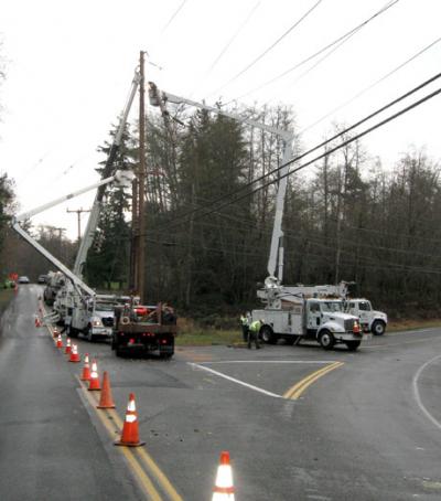You can see the top 30 feet of a power pole that broke, hanging in the air, while Puget Sound Energy workers set a new pole and transfer the high voltage lines to the new pole. 
