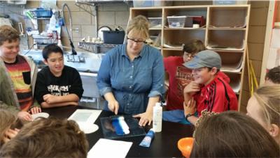 Alisara Martin (center) demonstrates how to make block prints with Harbor School 7th graders.